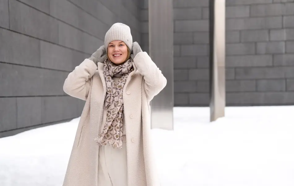 Dame med hvit lue, skjerf, hvit kåpe og bukse og grå votter