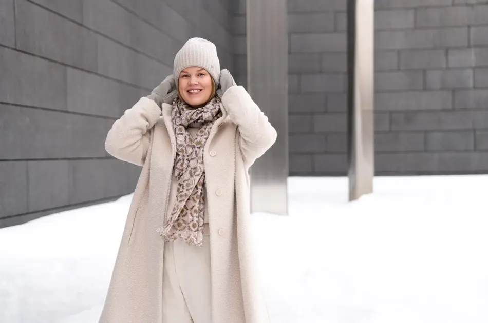 Dame med hvit lue, skjerf, hvit kåpe og bukse og grå votter