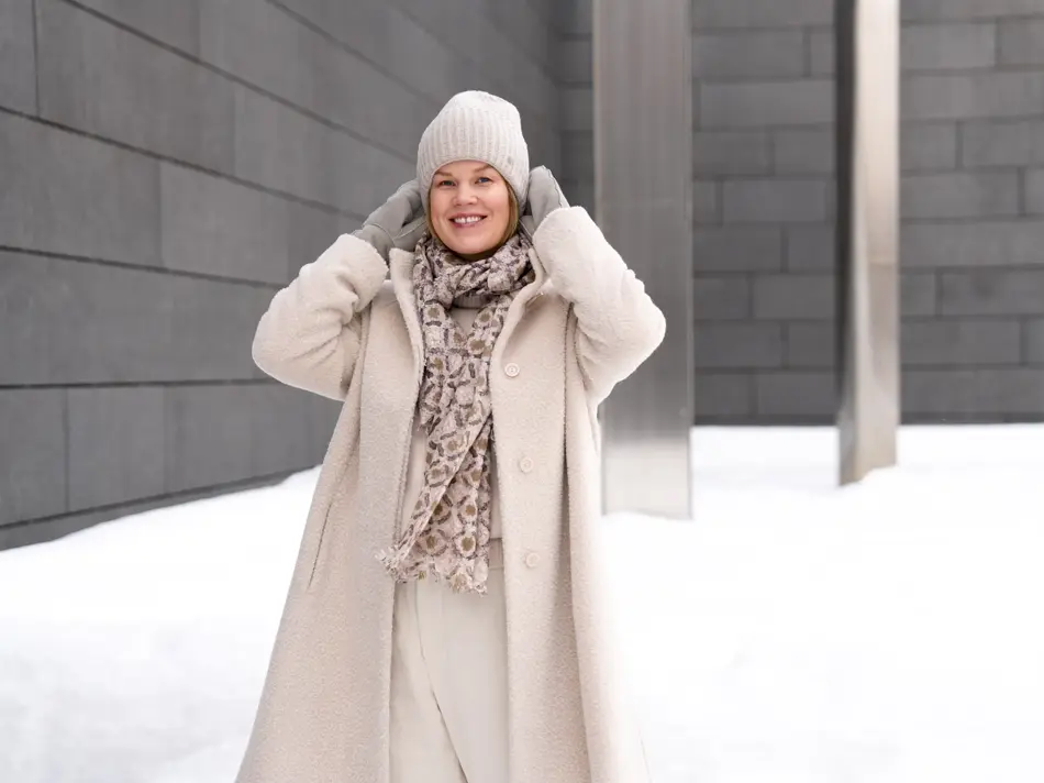 Dame med hvit lue, skjerf, hvit kåpe og bukse og grå votter