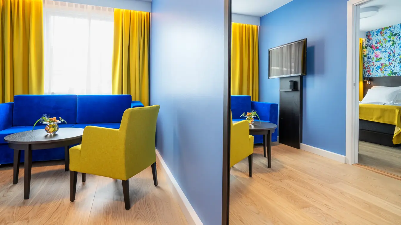 Sittegruppe med blå soffa og gule stoler i suite på Thon Hotel Moldefjord