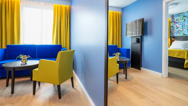 Sittegruppe med blå soffa og gule stoler i suite på Thon Hotel Moldefjord