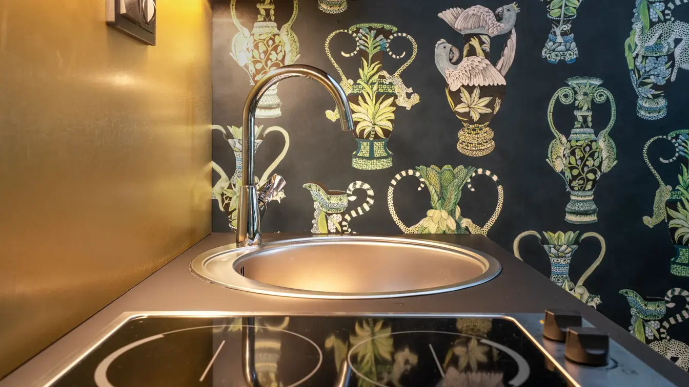 Kjøkken med spis og vask og mønstrete tapet med grønne detaljer i junior suite på Thon Hotel Linne