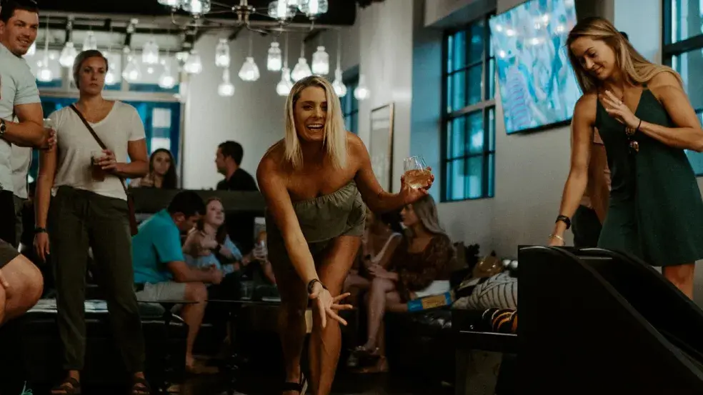 Dame spiller duckpin med folk rundt seg