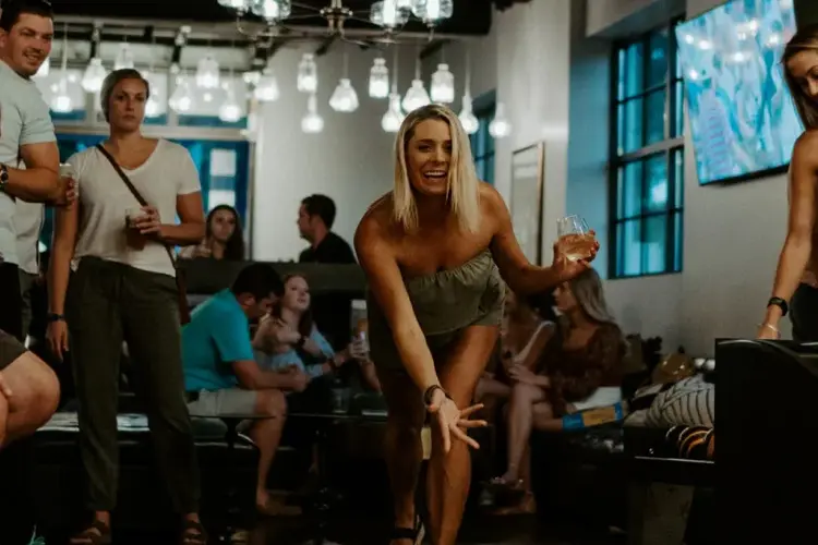 Dame spiller duckpin med folk rundt seg