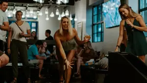 Dame spiller duckpin med folk rundt seg