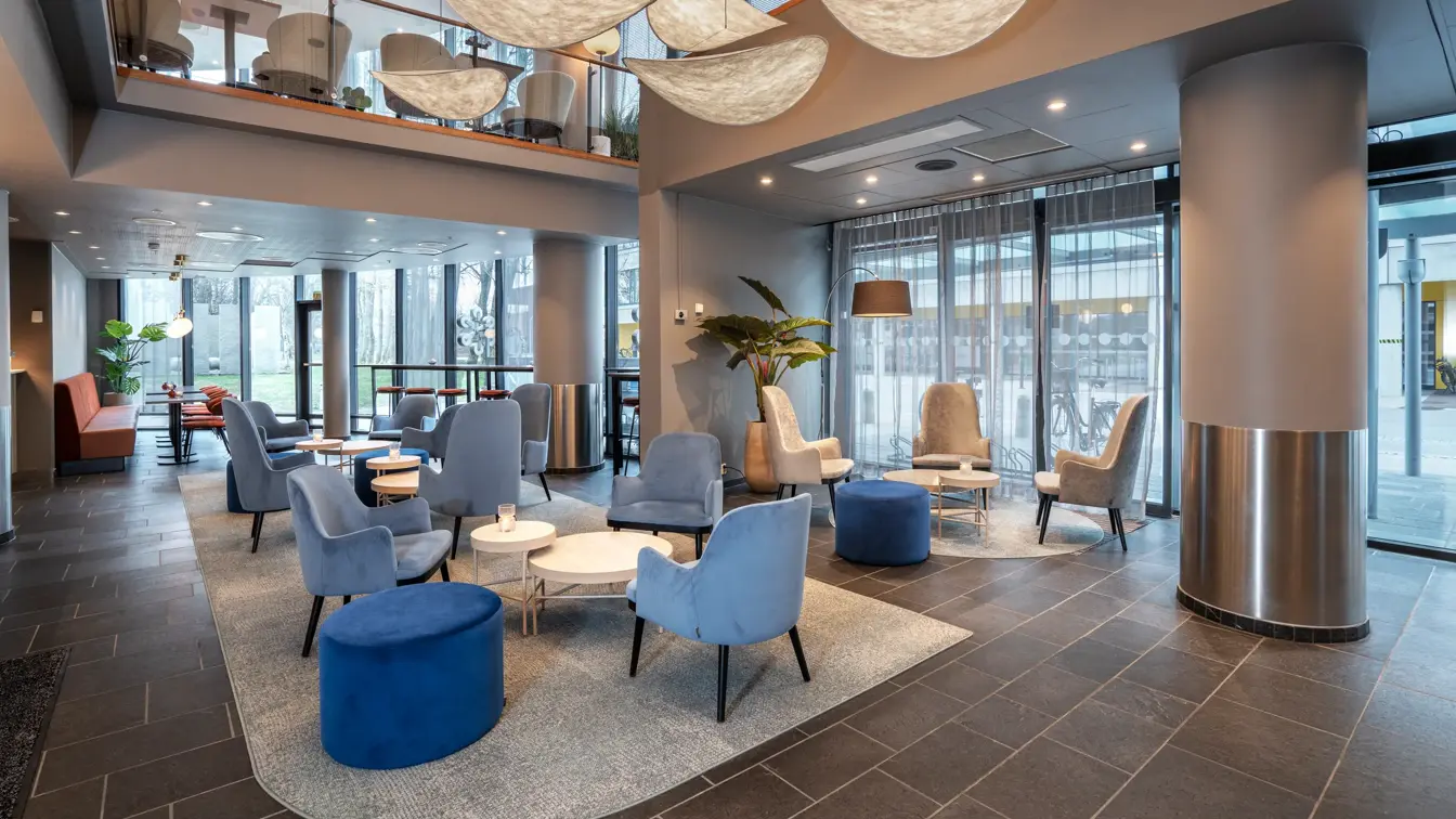 Lobbyen har hvilestoler, puffer, avlastningsbord og sofa, stoler og spisebord. Barkrakker ved vinduene, gulv-til-tak-vinduer. Flisbelagt gulv med tepper under hvilestoler.