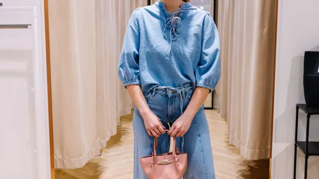 dame i vårklær står ved prøverom