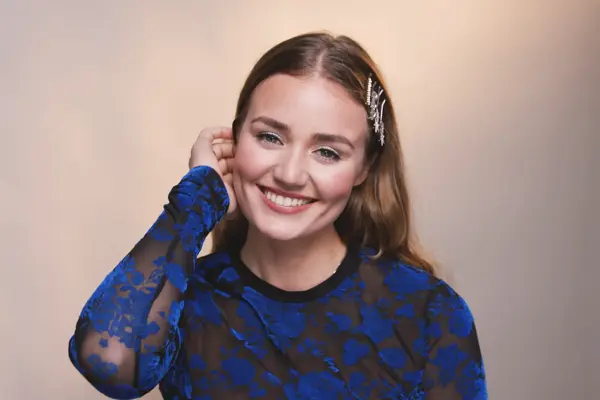 Smilende jente med festsminke fester håret bak øret