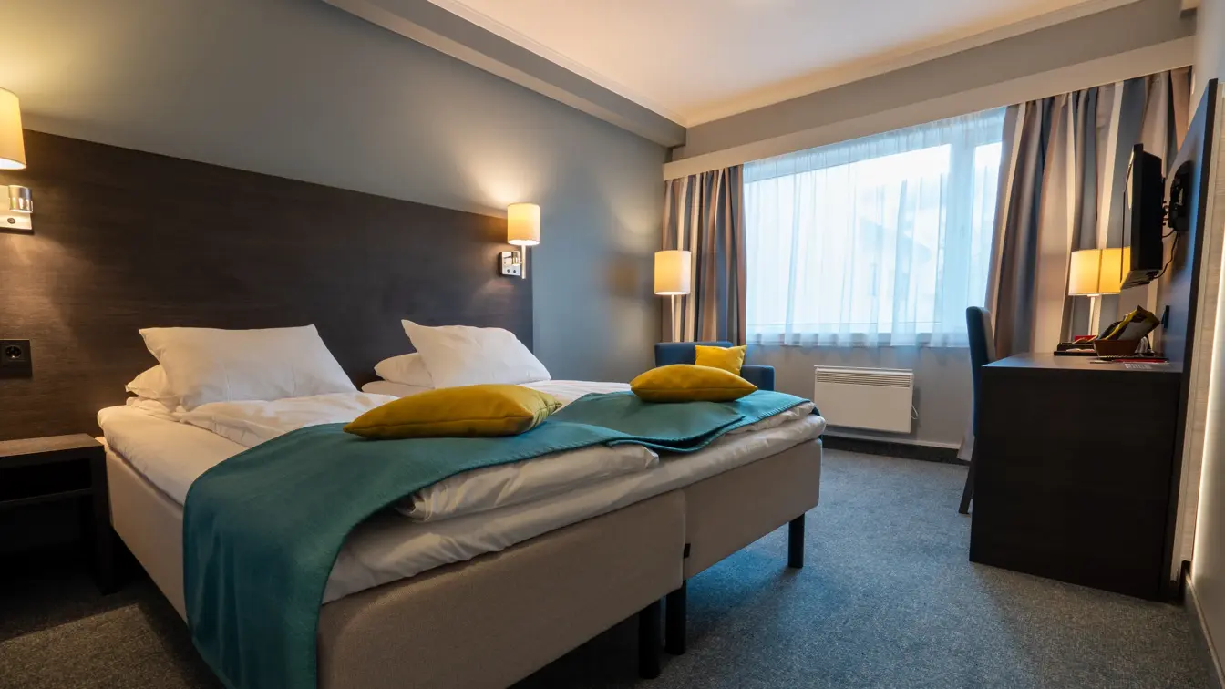 Dobbeltseng, vindu, skrivepult, TV, stol, lamper