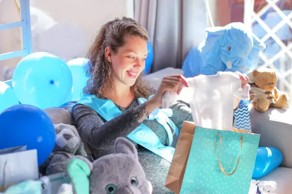 a Young pregnant woman opening presents at her baby shower.