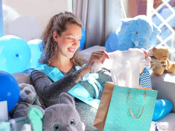 a Young pregnant woman opening presents at her baby shower.