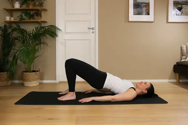 Anna viser Pilates-øvelser på treningsmatte på gulvet