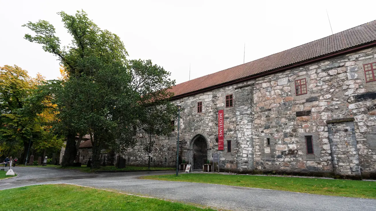 Museum i murstein sett fra siden med grønt gress og trær rundt