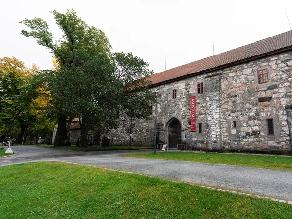 Museum i murstein sett fra siden med grønt gress og trær rundt