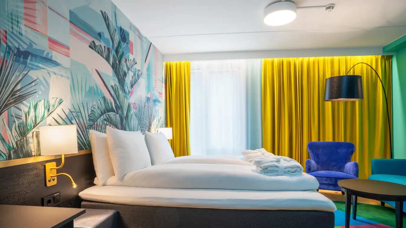 Dobbeltseng, fargerik palmetapet og blå stol i superior HCP rom på Thon Hotel Storo