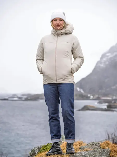 Dame som står på et berg med utsikt over sjøen