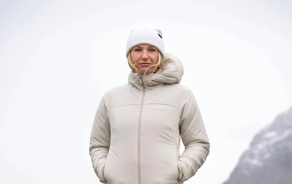 Dame som står på et berg med utsikt over sjøen