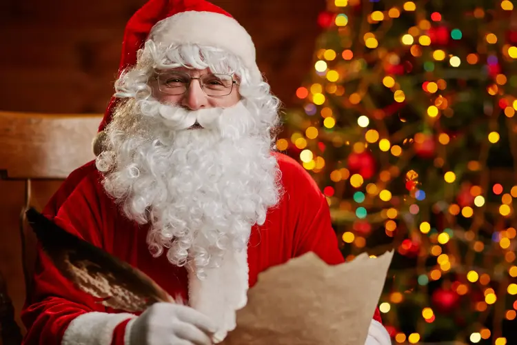 Senior man in costume of Santa Claus holding feather and Christmas letter