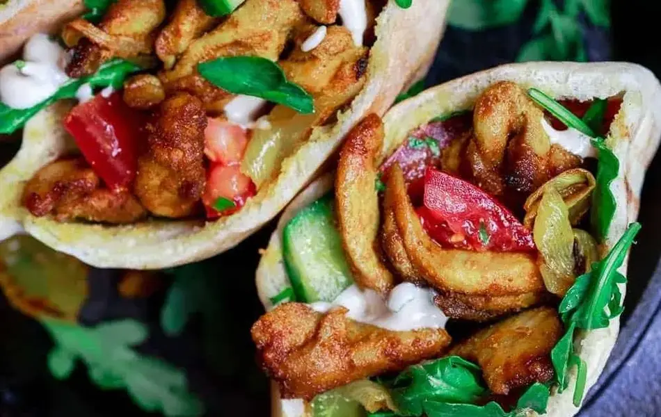 Tre kyllingkebab i pitabrød, stående i jernpanne