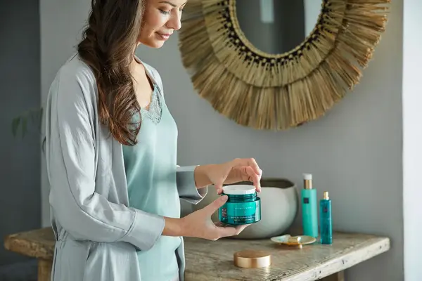 kvinne som åpner en krukke med rituals på badet