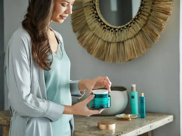 kvinne som åpner en krukke med rituals på badet