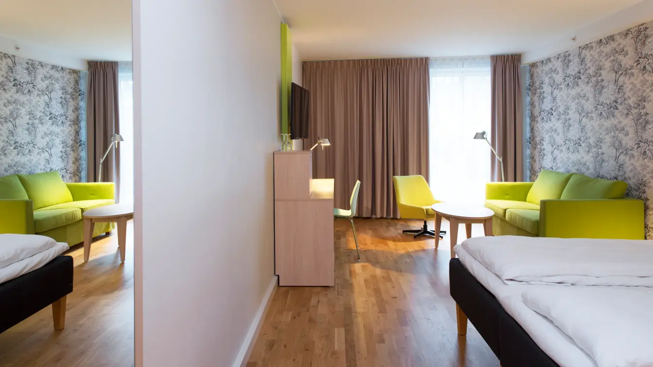 Dobbeltseng med blomstertapet, tv og skrivepult på familie room på Thon Hotel Sandven i Nordheimsund