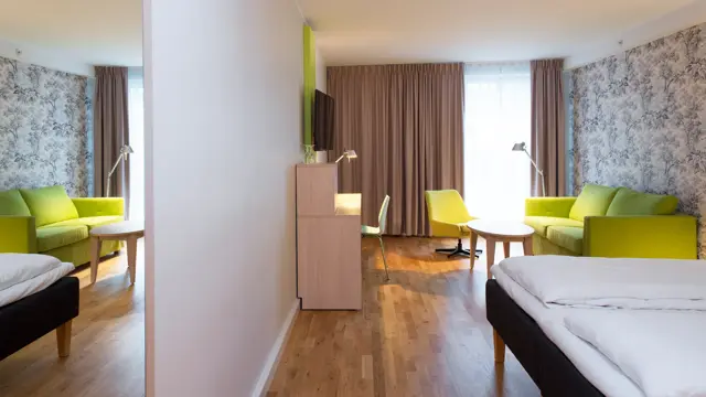 Dobbeltseng med blomstertapet, tv og skrivepult på familie room på Thon Hotel Sandven i Nordheimsund