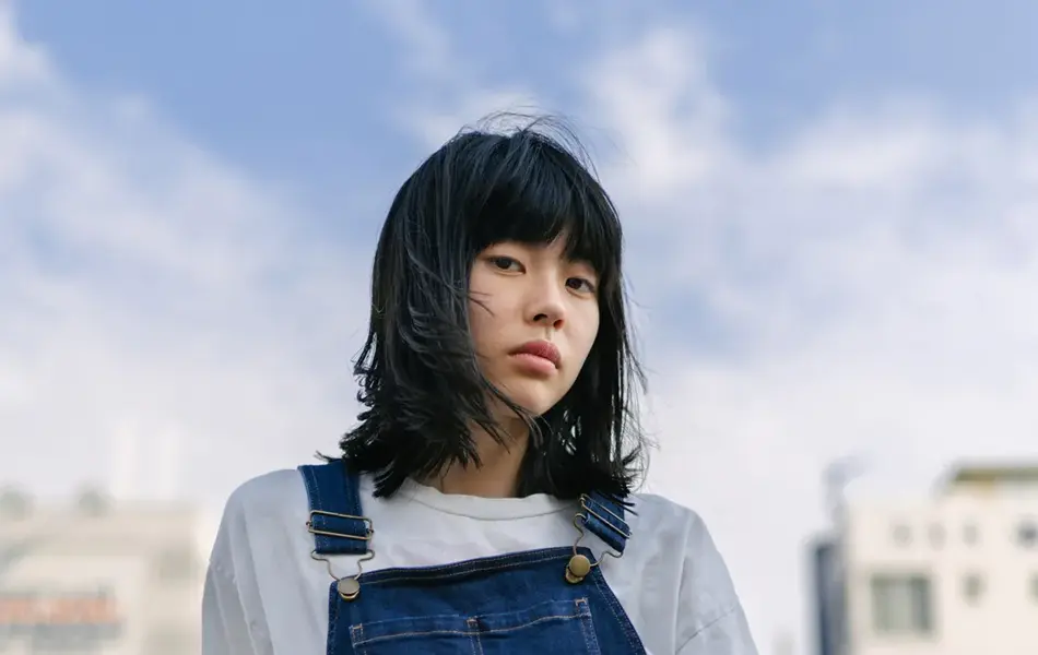 Kvinne i jeans poserer utendørs med vind i håret