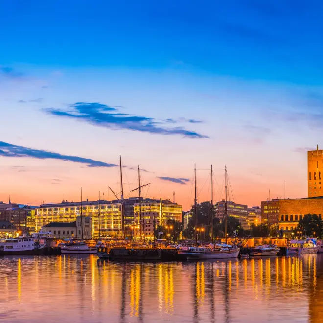 Summer sunset skies over the illuminated landmarks of Oslo's downtown waterfront, from the busy bars and restaurants of Aker Brygge, the popular leisure district, to the iconic twin towers of City Hall, Radhus, and the crowded marina on the tranquil waters of OsloFjorden, Norway. ProPhoto RGB profile for maximum color fidelity and gamut.
