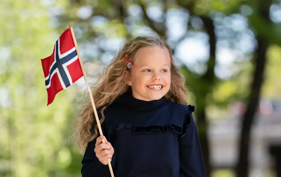 Jente står ute og holder et flagg i mørk blå kjole.