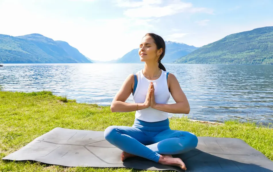 anny johansen viser yogaøvelser ute foran vakker fjord
