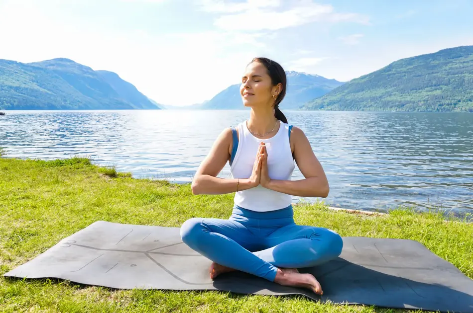 anny johansen viser yogaøvelser ute foran vakker fjord