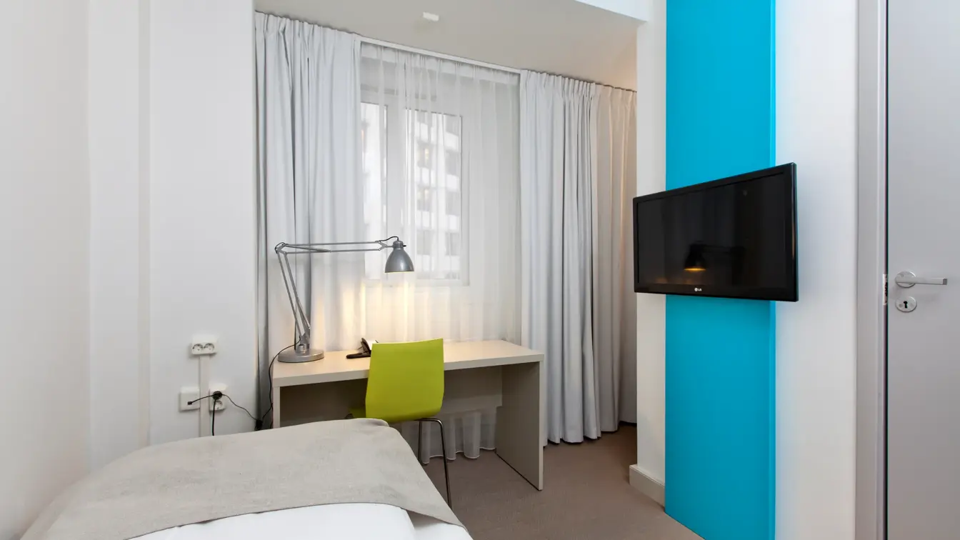 Seng, skrivebord og TV i enkeltrom på Thon Hotel Munch i Oslo