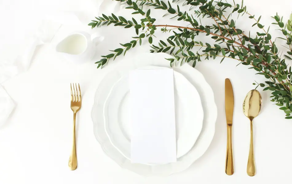 Festive wedding, birthday table setting with golden cutlery, eucalyptus parvifolia branch, porcelain plate, milk and silk ribbon. Blank card mockup. Rustic restaurant menu concept, flat lay, top view