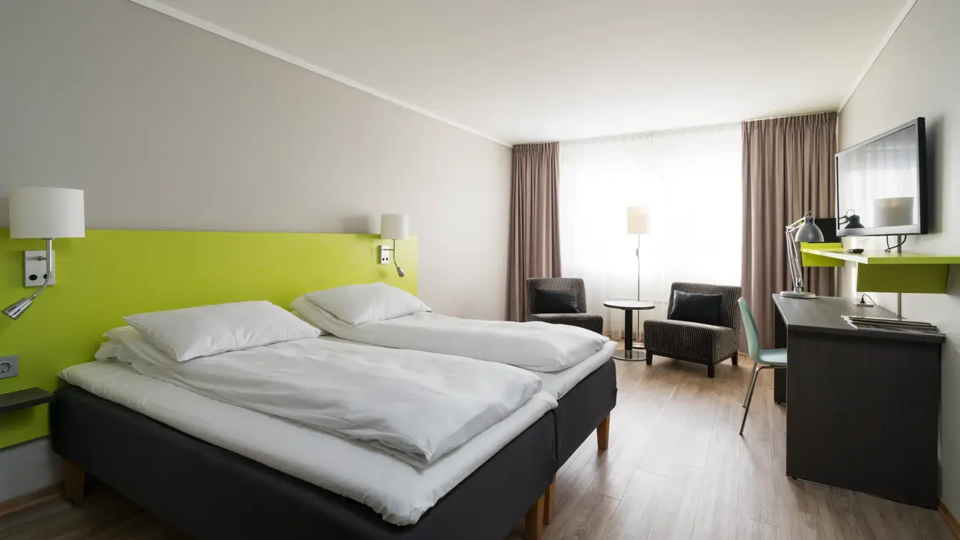 Seng, liten sittegruppe, skrivebord og TV i standard twin rom på Thon Hotel Hallingdal