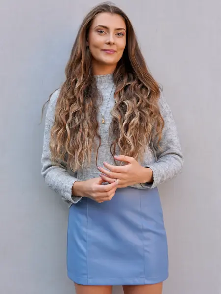 Dame med blått skinn skjørt og grå genser