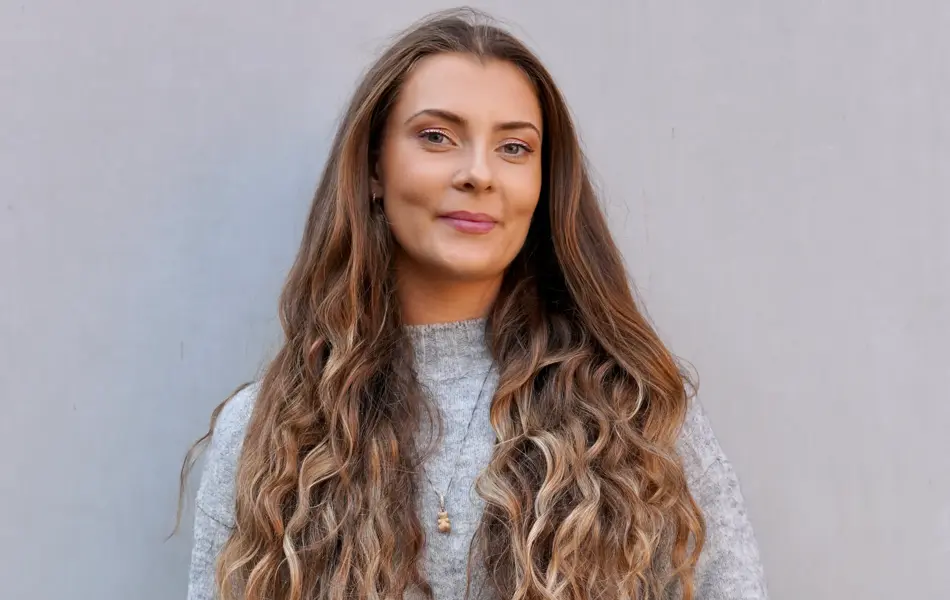 Dame med blått skinn skjørt og grå genser