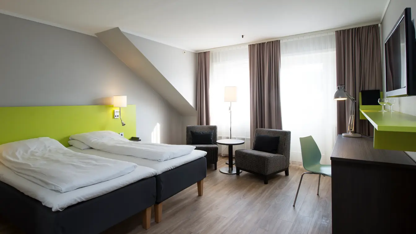 Seng, skrivebord, TV og liten sittegruppe i dobbeltrom på Thon Hotel Hallingdal