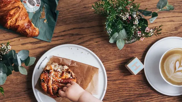 Hånd rekker over et bord å tar i mat
