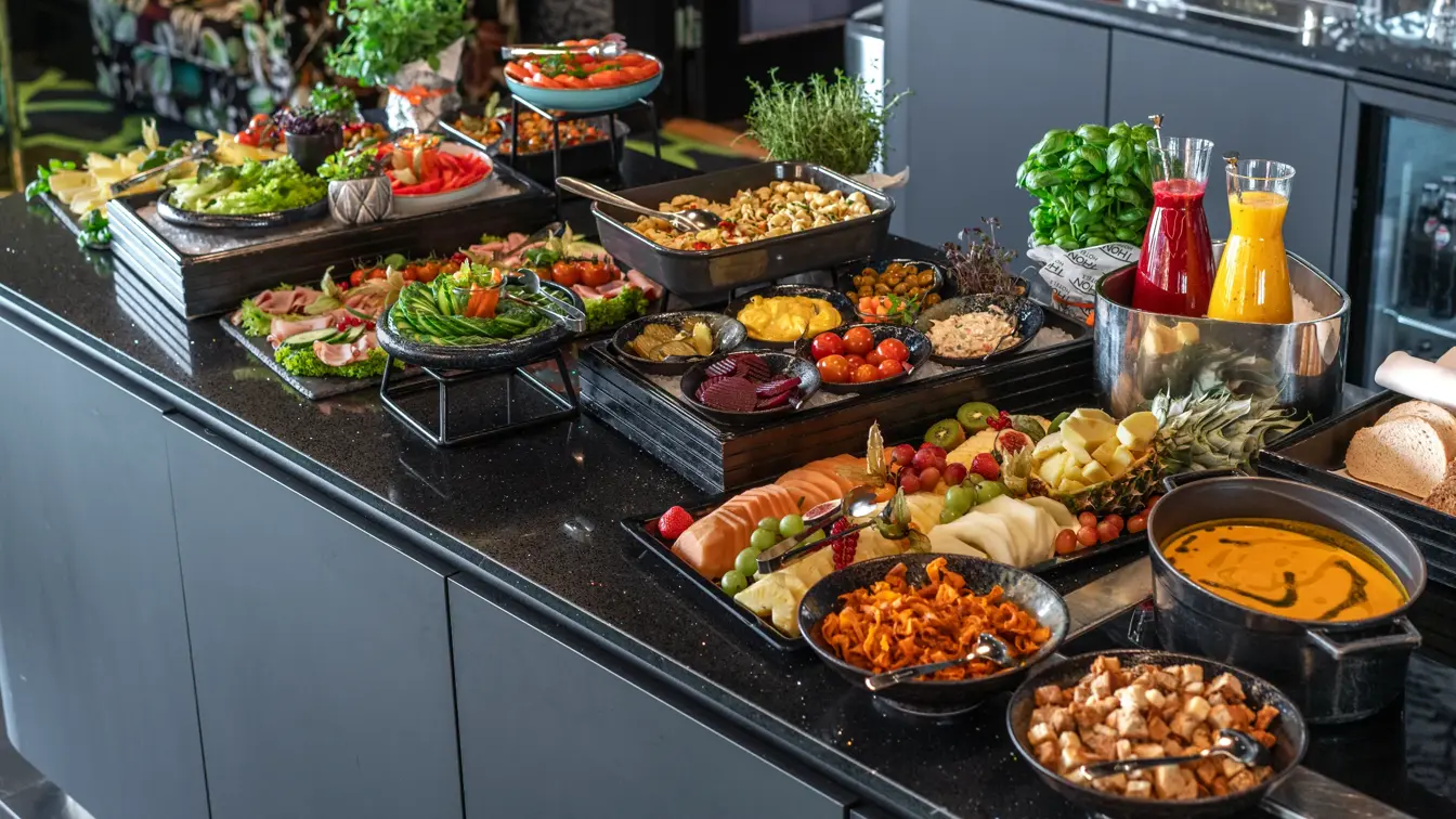 Kveldsmat på buffet med fargerike oppkuttede grønnsaker og frukt, suppe med tilbehør.